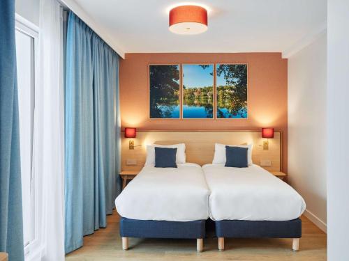 a bedroom with two beds and two windows at Aparthotel Adagio Paris Boulogne in Boulogne-Billancourt