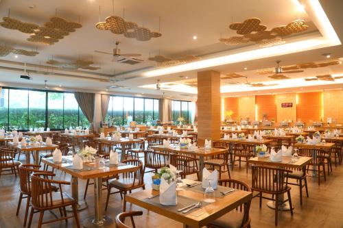 a restaurant with wooden tables and chairs and windows at CRAFT Resort & Villas, Phuket Town - scheduled shuttle to Phuket Old Town in Phuket