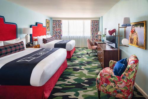 a hotel room with two beds and a desk at Graduate by Hilton Fayetteville, AR in Fayetteville