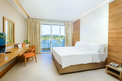 a bedroom with a bed and a desk and a window at Pattana Sports Resort in Si Racha