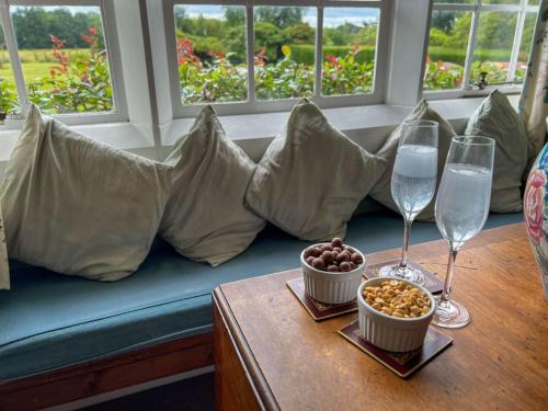 a table with two wine glasses and a bowl of nuts at Bank House Longtown in Longtown