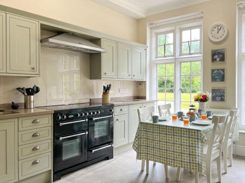 a kitchen with a stove and a table with chairs at Bank House Longtown in Longtown