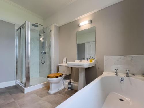 a bathroom with a tub and a toilet and a sink at Bank House Longtown in Longtown