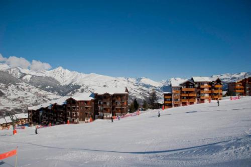 un lodge de ski sur une piste de ski avec des montagnes enneigées dans l'établissement Les Choucas, à Aime La Plagne
