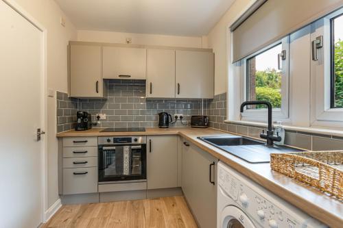 a kitchen with white cabinets and a sink and a window at Abbey View in Melrose