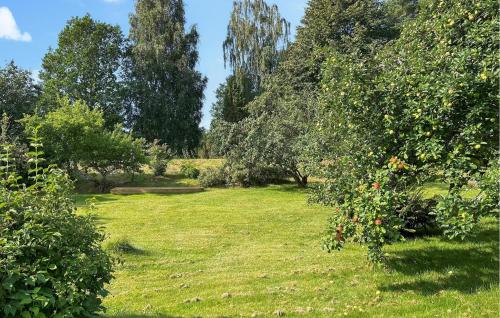 a garden with trees and grass with red apples at 2 Bedroom Awesome Home In Växjö in Växjö