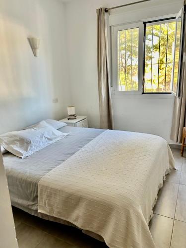 a white bed in a bedroom with a window at Tranquil setting in Moraira