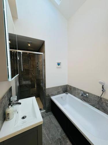 a bathroom with a tub and a sink and a shower at Totterdown House with Views & Garden in Bristol