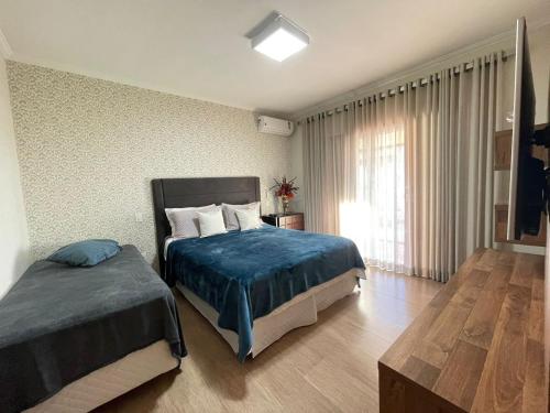 a bedroom with two beds and a window at Casa Alto da Boa Vista in Serra Negra