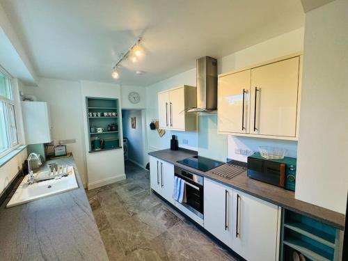 a kitchen with white cabinets and a sink at Totterdown House with Views & Garden in Bristol