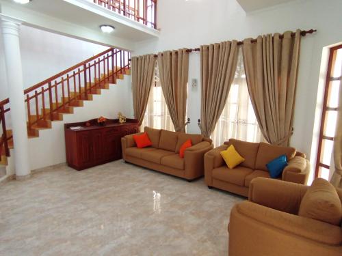 a living room with two couches and a staircase at Calm Nature Villa in Matara