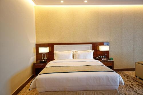 a hotel room with a large bed with two lamps at Royal Swiss Lahore in Lahore