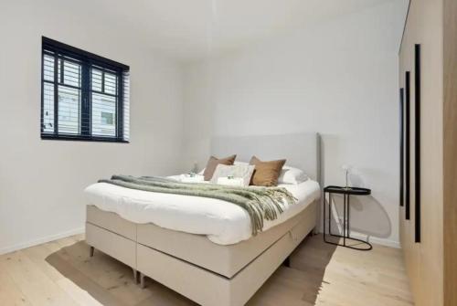 ein weißes Schlafzimmer mit einem weißen Bett und einem Fenster in der Unterkunft Triton luxe gelijkvloers appartement met tuin en gratis garage in Knokke-Heist