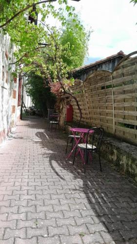 une table de pique-nique rose et des chaises sur un trottoir en briques dans l'établissement Le Domaine, à Moustey