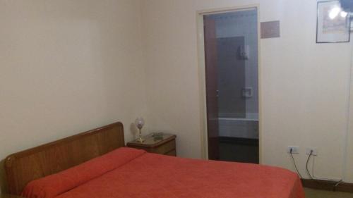 1 dormitorio con 1 cama con edredón rojo y puerta en Hotel guido palace, en Buenos Aires