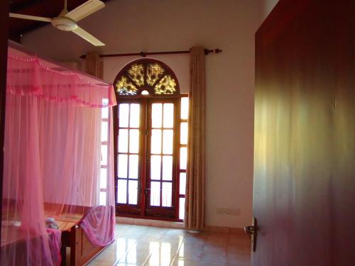 a room with a door and a window with pink curtains at Calm Nature Villa in Matara
