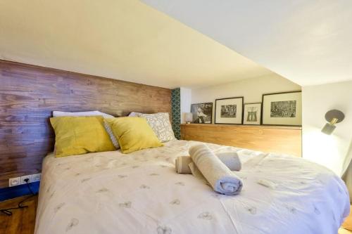 - une chambre avec un grand lit blanc et des oreillers jaunes dans l'établissement Cosy studio proche de la Basilique du Sacré-Coeur, à Paris