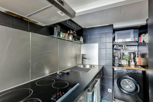 une petite cuisine avec un évier et une machine à laver dans l'établissement Cosy studio proche de la Basilique du Sacré-Coeur, à Paris