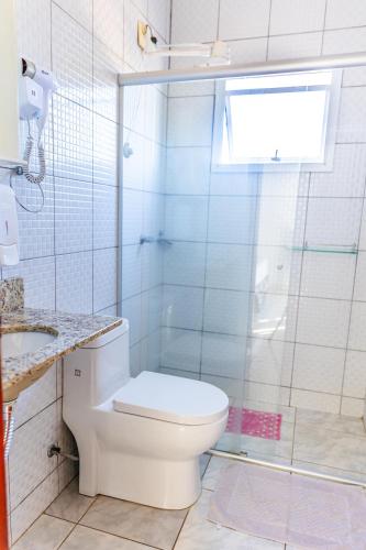 a white bathroom with a toilet and a shower at Teuthos Hotel in Teutônia