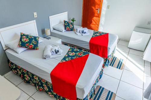 two beds in a room with red and green blankets at Teuthos Hotel in Teutônia