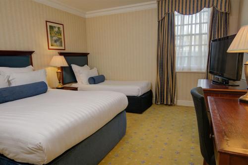 a hotel room with two beds and a flat screen tv at Manor Hotel Solihull, BW Signature Collection in Bickenhill