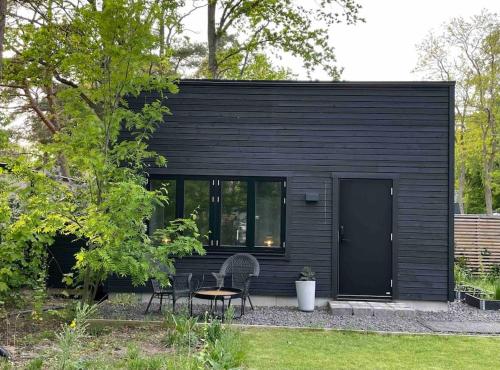 a black house with two chairs and a table at Nybyggt gästhus i vacker omgivning in Höllviken