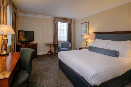 a hotel room with a bed and a desk and a television at Manor Hotel Solihull, BW Signature Collection in Bickenhill