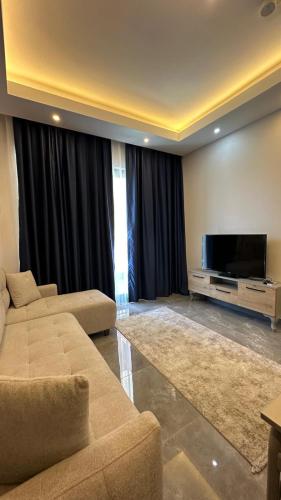 a living room with a couch and a flat screen tv at Silece garden suite iki yatak odalı daire in Alanya