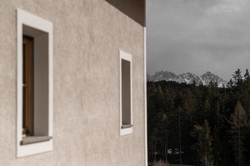 two windows of a building with a view of a forest at Haus Engadein in Auna di Sopra