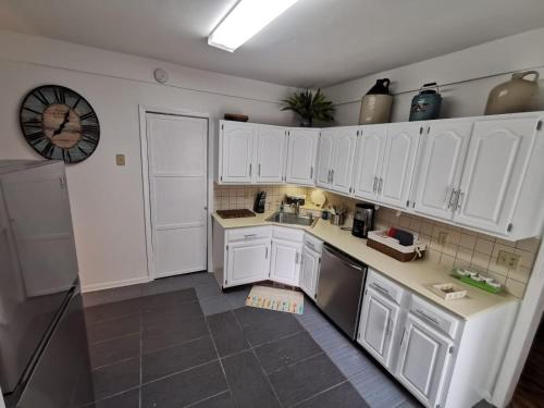 a kitchen with white cabinets and a clock on the wall at Prime location! 4 bedroom house located right next to the casino and the falls in Niagara Falls