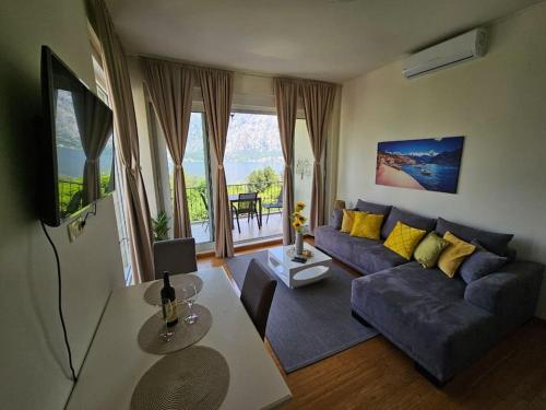 ein Wohnzimmer mit einem blauen Sofa und gelben Kissen in der Unterkunft Deniz Apartment Kotor bay view apartment with terrace and pool in Prčanj