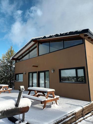 a house with a picnic table in the snow at Cabañas Abedul in Villa Meliquina