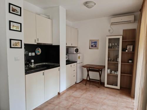 a kitchen with white cabinets and a wooden table at Марина Кейп in Aheloy