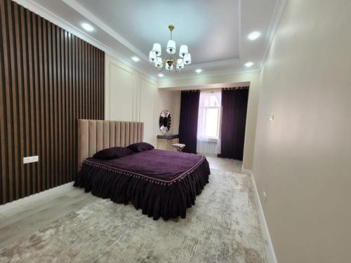 a bedroom with a purple bed and a chandelier at квартира in Aktau