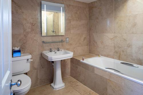 a bathroom with a sink and a tub and a toilet at The Wood Norton in Evesham