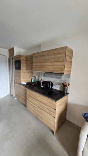 une cuisine avec des armoires en bois et un comptoir noir dans l'établissement Studio à Sainte-Maxime, à Sainte-Maxime