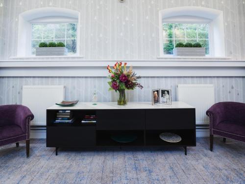 a living room with a table with a vase of flowers at The Wood Norton in Evesham