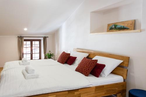 a bedroom with a large white bed with red pillows at Wellba Homestead Planina in Ajdovščina
