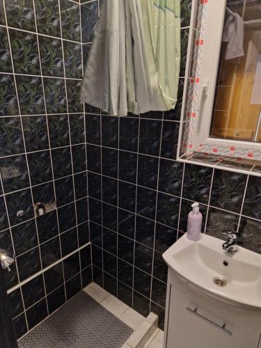 a black tiled bathroom with a sink and a mirror at Orion in Mąchocice
