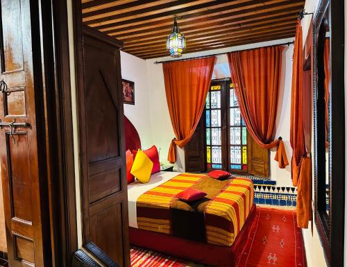 a bedroom with a bed with orange and yellow pillows at Riad Ahlam in Fès