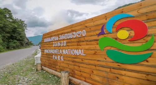 a sign on a wooden wall next to a road at Nepoka in Machakhela in Tsʼkhemlisi