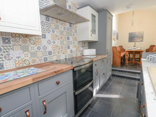 a kitchen with white cabinets and tiles on the wall at Home From Home in Portland