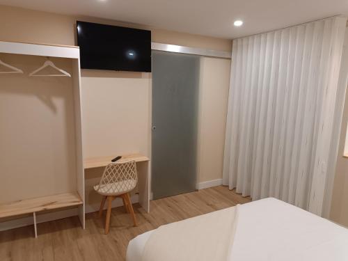 ein Schlafzimmer mit einem Bett, einem Schreibtisch und einem Fernseher in der Unterkunft Pensión Vázquez in Vimianzo