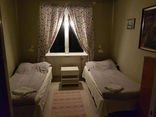 two beds in a small room with a window at Holmstagården in Bispgården