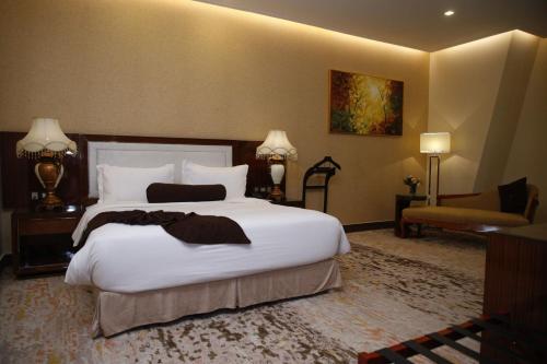 a bedroom with a large white bed and a chair at Royal Swiss Lahore in Lahore