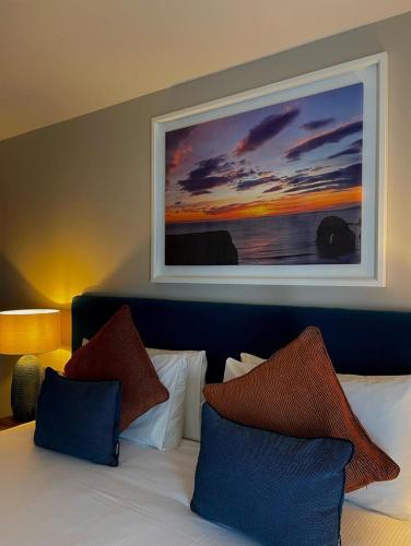 a bedroom with a bed with a painting on the wall at Rooms at The Marine in Ballybunion