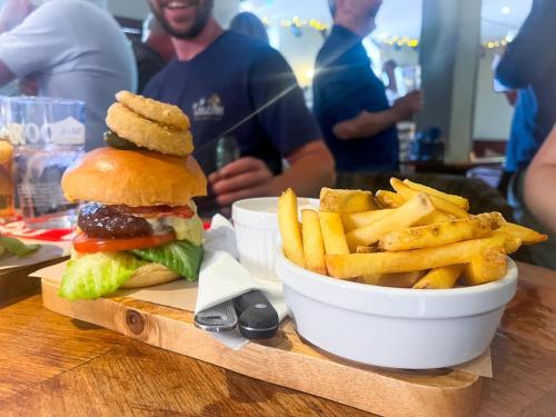 - un hamburger et des frites sur un plateau en bois dans l'établissement Daisy Cottage, à Child Okeford