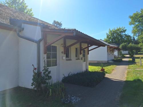 a small white house with a wooden roof at Landidyll Monte Gristow in Mesekenhagen