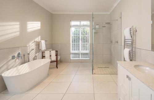 a white bathroom with a tub and a sink at The Plettenberg Hotel in Plettenberg Bay