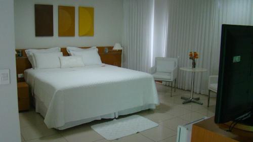 a bedroom with a white bed and a television at Hotel Elite 1 in Nossa Senhora dos Milagres